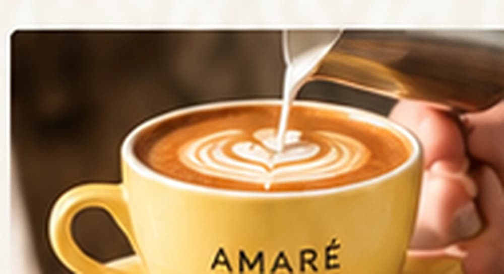 Barista sirviendo leche sobre un latte